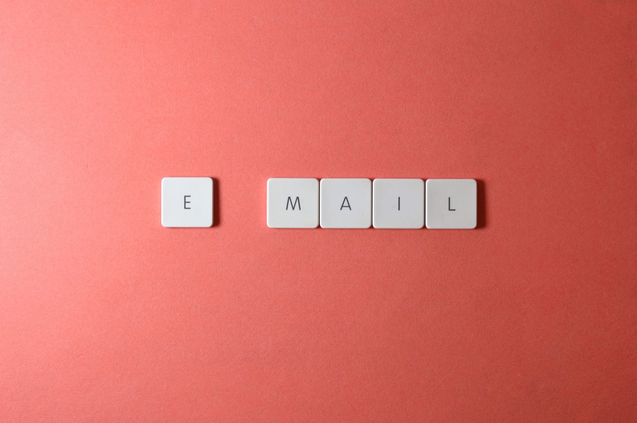 team-03 Flat lay of keyboard letter tiles arranged to spell email against a coral background.
